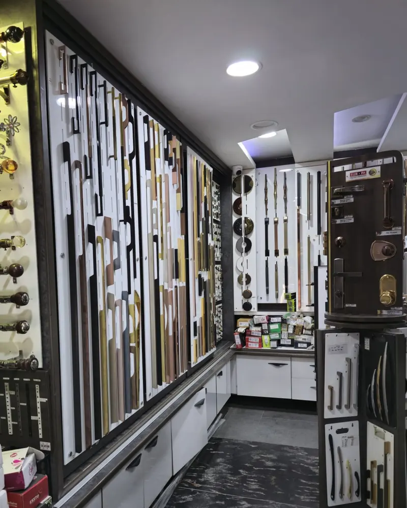 Inside Eddi Hardware: a wall of long cabinet handles in brass, black and copper finishes beside a back-lit wall of curtain rods